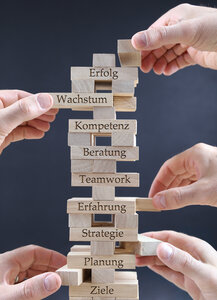 Ein Turm aus Spielbausteinen beschriftet mit Erfolg, Wachstum, Kompetenz, Beratung